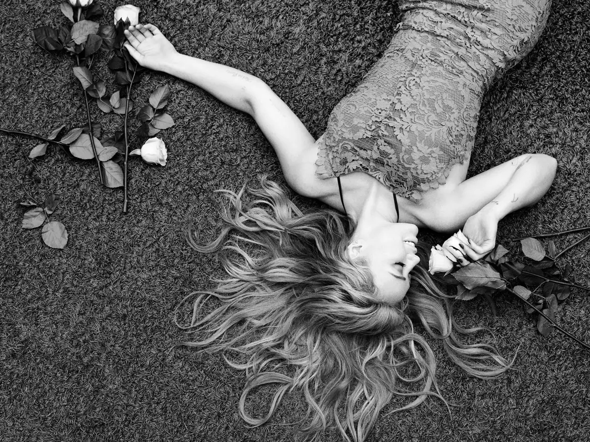 Hilary Duff recostada en el pasto con rosas, en blanco y negro